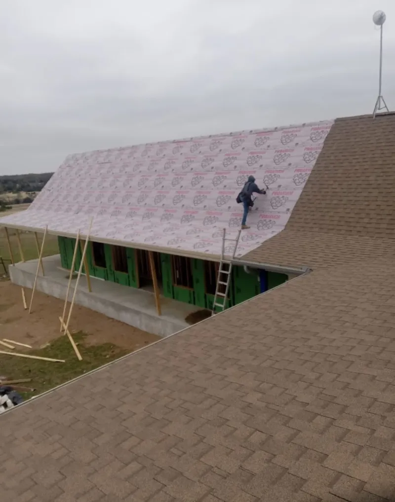 Worker preparing underlayment for a metal roof installation in Kasson